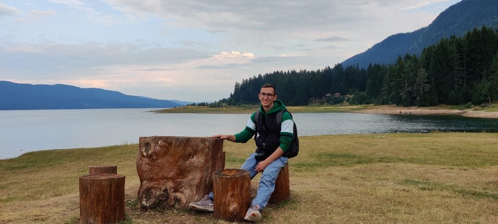 A happy man sitting near a lake